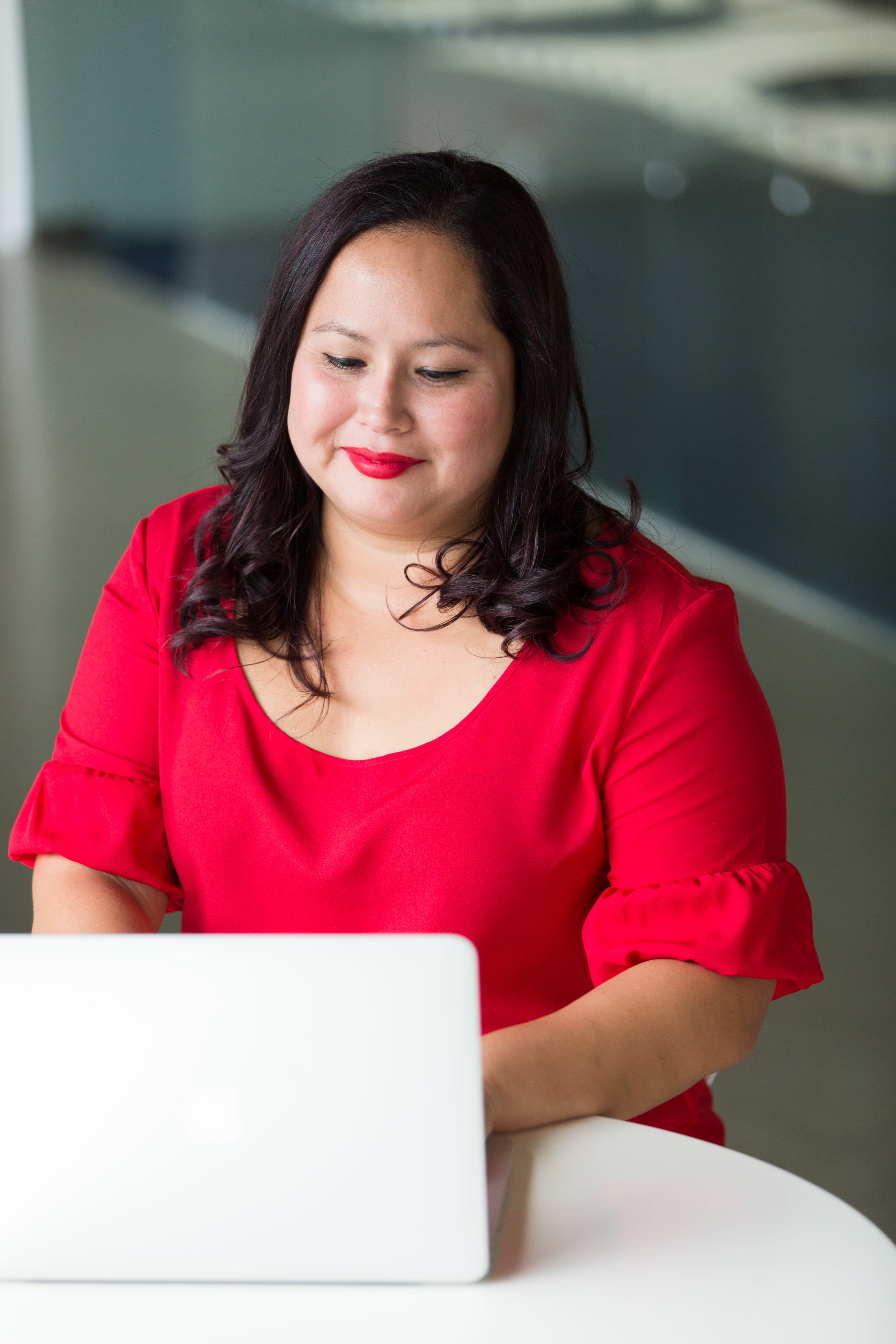Woman wearing red top using laptop computer
